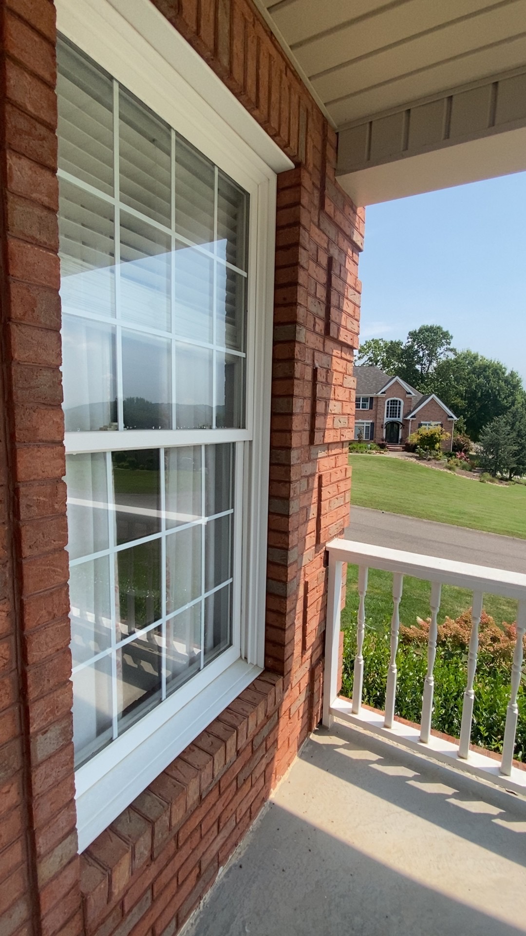 Crystal clear front porch window reflecting the neighborhood