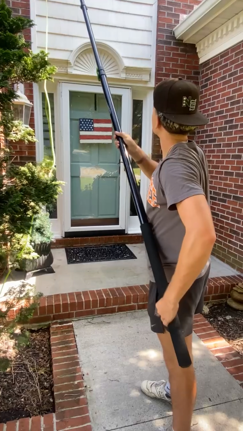 Archer Exterior Cleaning technician using a water-fed pole to clean windows on a brick home